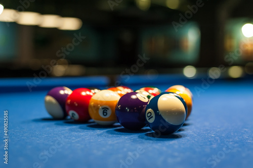 multicolored billiard balls lie in a triangle on a table with a blurred background