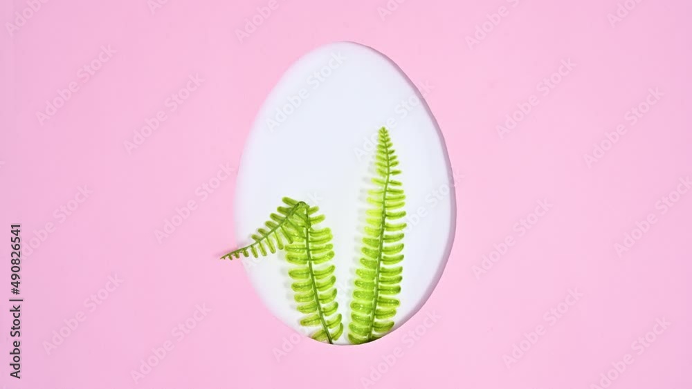 Creative rabbit ears appear in egg shape frame on pastel pink background. Creative Easter concept. Stop motion flat lay Creative rabbit ears appear in egg shape frame on pastel pink background. Creative Easter concept. Stop motion flat lay