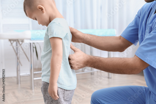 Orthopedist examining child's back in clinic, closeup. Scoliosis treatment photo