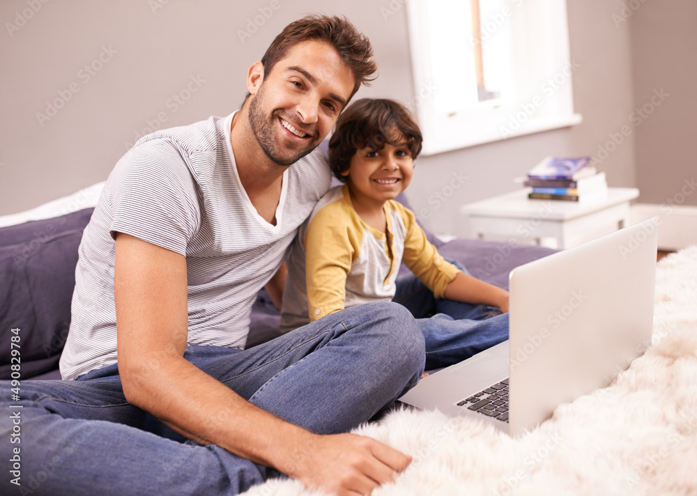 Theres always something to smile about. Portrait of a father and son sitting on bed with their laptop. Theres always something to smile about. Portrait of a father and son sitting on bed with their laptop.