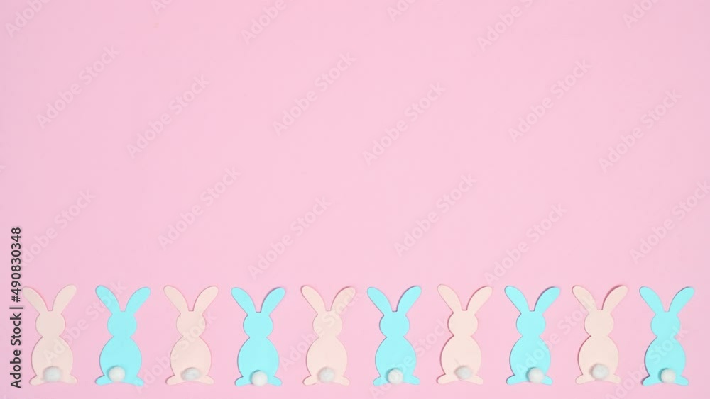 Pastel pink and blue rabbits appear on bottom of bright pink background. Flat lay. copy space stop motion Pastel pink and blue rabbits appear on bottom of bright pink background. Flat lay. copy space stop motion