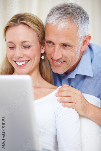 E-mailing family abroad. A young married couple working on their laptop at home.