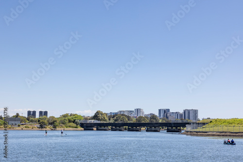 Paddleboards and boat on the Cooks River, Sydney, looking back over General Holmes drive and Wolli Creek 
