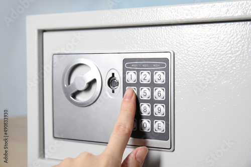 Принти на полотні Woman dialing combination on keypad of steel safe, closeup