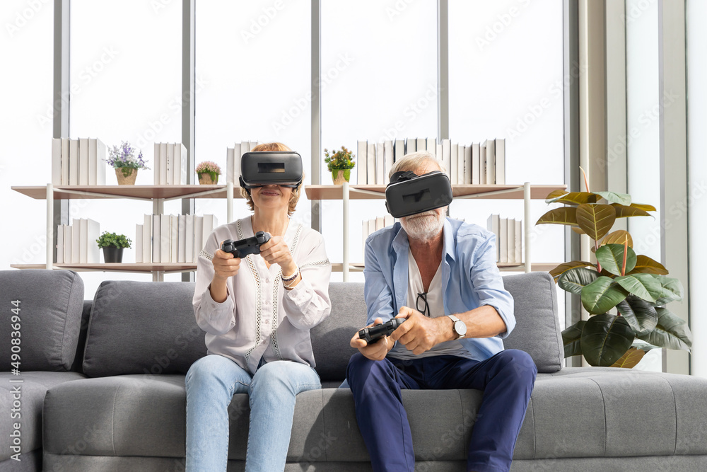 Obraz premium senior couple playing game and having fun together with virtual reality headset on the sofa