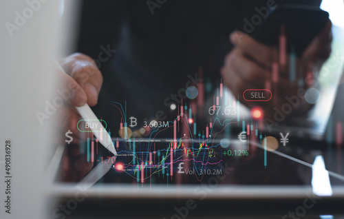 Business man using digital tablet monitoring with forex trading graph, analysis graph of stock market financial data, stock exchange and world currency © tippapatt