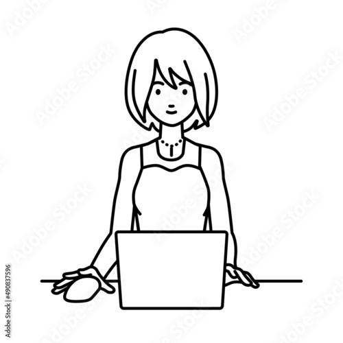 デスクで座ってPCを使っているドレスの女性