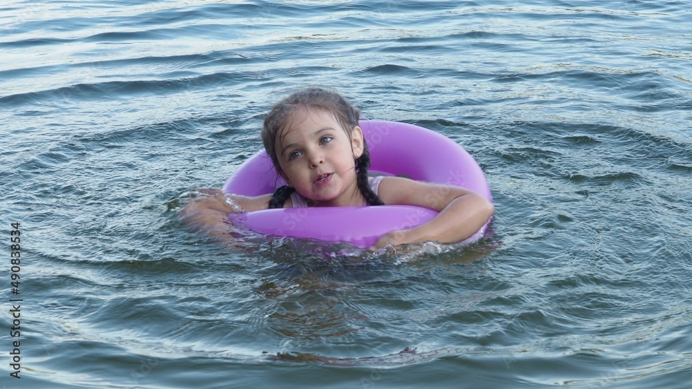 Girl Children swim with rubber circle for swimming. Camping in summer. Active recreation on the water. Girl in an inflatable circle. happiness, holidays, rest