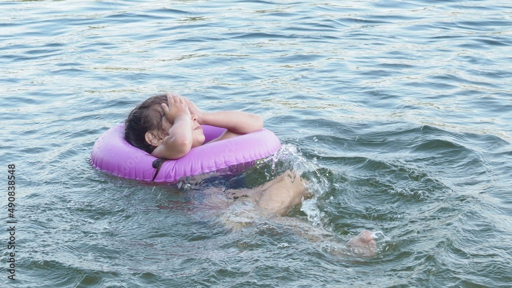 Girl Children swim with rubber circle for swimming. Camping in summer. Active recreation on the water. Girl in an inflatable circle. happiness, holidays, rest Girl Children swim with rubber circle for swimming. Camping in summer. Active recreation on the water. Girl in an inflatable circle. happiness, holidays, rest