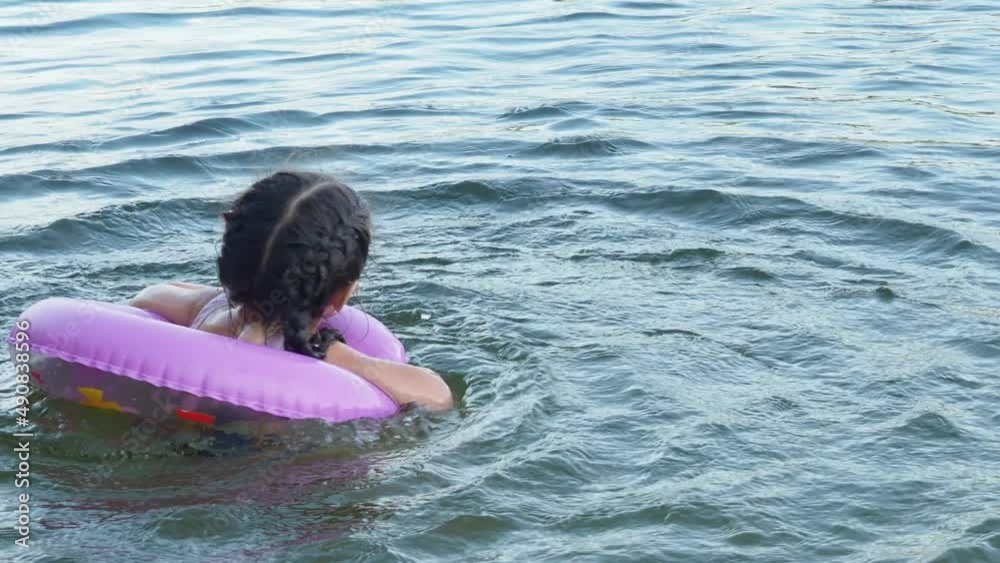 Girl Children swim with rubber circle for swimming. Camping in summer. Active recreation on the water. Girl in an inflatable circle. happiness, holidays, rest Girl Children swim with rubber circle for swimming. Camping in summer. Active recreation on the water. Girl in an inflatable circle. happiness, holidays, rest