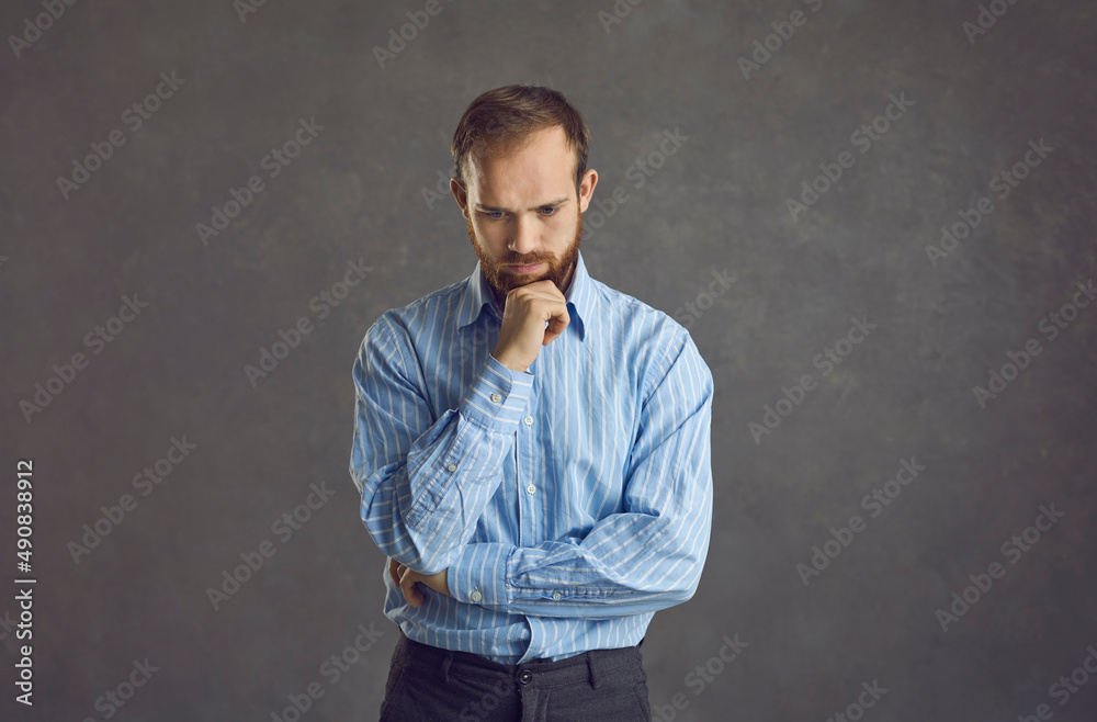 Adult handsome man in casual t-shirt standing over grey background feeling confuse and wonder about question studio portrait headshot. Uncertain with doubt, thinking with hand on head. Pensive concept