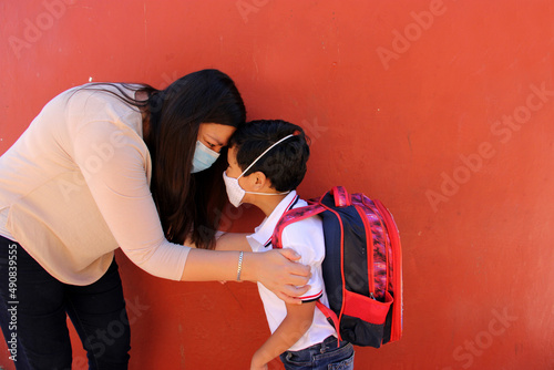 Latino mom and son prepare to go back to school with a backpack and face mask as protection from Covid-19 in the new normality due to the Coronavirus pandemic
 photo