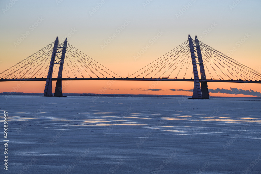 Fototapeta premium The silhouette of the cable-stayed bridge over the Ship Fairway on the Western High-Speed ​ ​ Diameter against the background of the December sunset. St. Petersburg, Russia