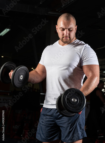 Male bodybuilder engaged with dumbbells in the gym