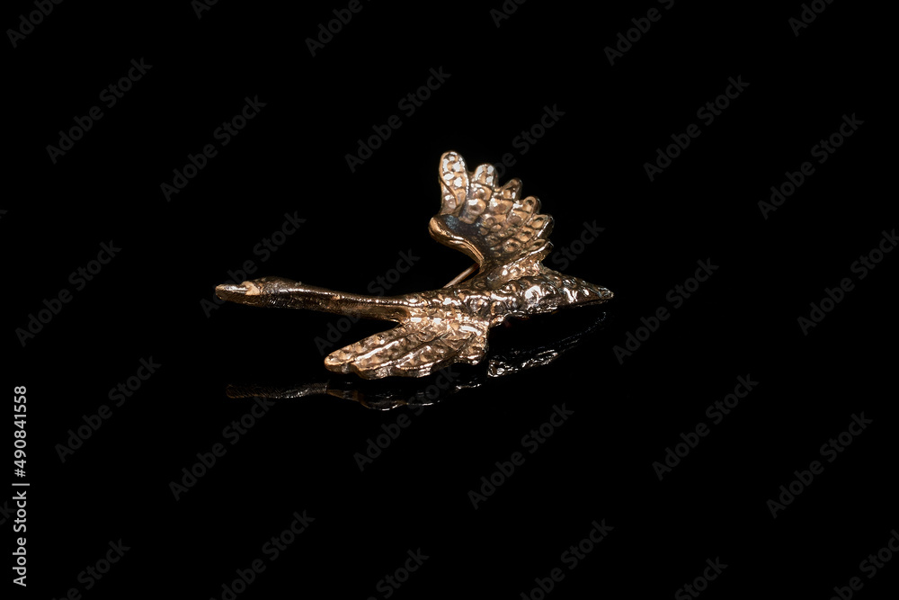 Silver brooch in the form of a flying swan on a black background