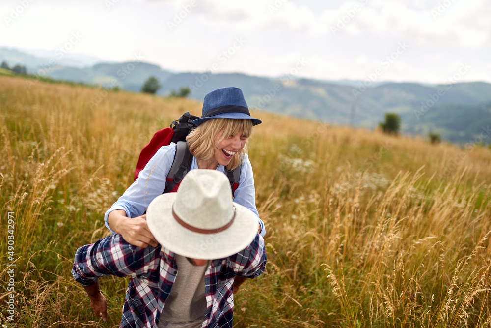 A young happy couple in love is having a good time while walking a meadow. Hiking, nature, relationship, together
