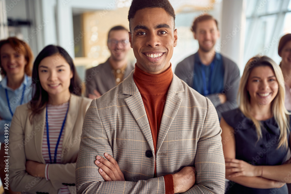 Obraz premium Close-up shot of a young cheerful businessman standing in the company building hallway with his colleagues and enjoys posing for a photo. Business, people, company
