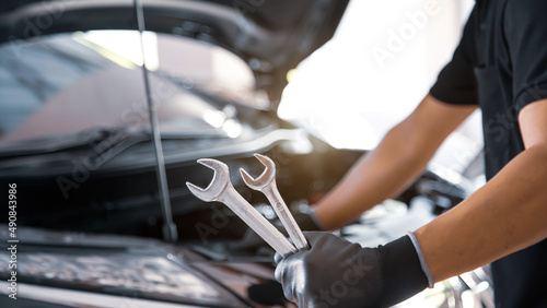 Close-up hand auto mechanic using the wrench to repairing car engine problem. Concepts of check and inspection car care maintenance and servicing. © Jintana