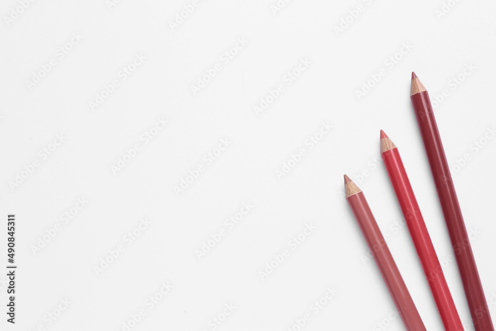 Different lip pencils on white background, top view. Cosmetic product Different lip pencils on white background, top view. Cosmetic product