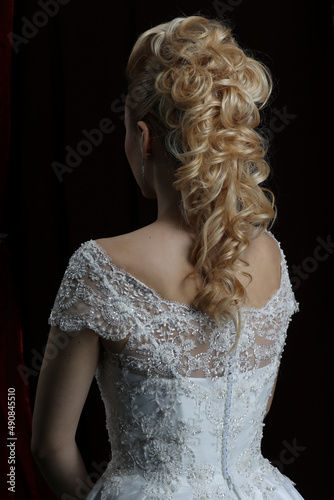 Blonde beauty hairstyle behind on a dark background beautiful.The long hair of the bride is neatly styled.