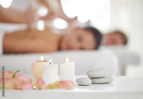 Blissful relaxation. A married couple receiving massages at a spa with candles in the foreground.