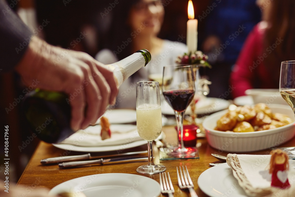 This calls for a celebration. Closeup shot of a person pouring wine into a glass at a dining table.