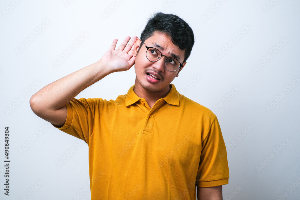 Young handsome asian man smiling with hand over ear listening an hearing to rumor or gossip. Deafness concept.