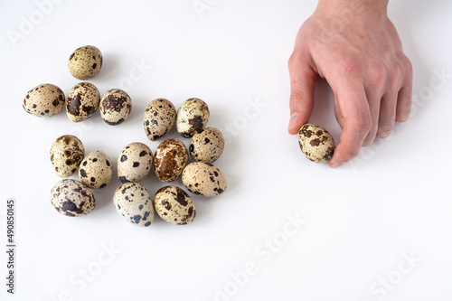 man's hand and quail eggs on a white background. Top view. The concept of a healthy breakfast. Home cooking
