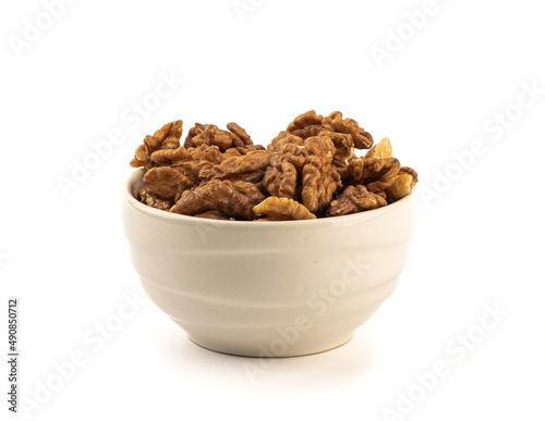 Peeled walnuts in a ceramic bowl on a white background.