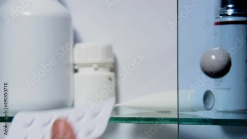 hand open medicine cabinet and pick up drug tablets