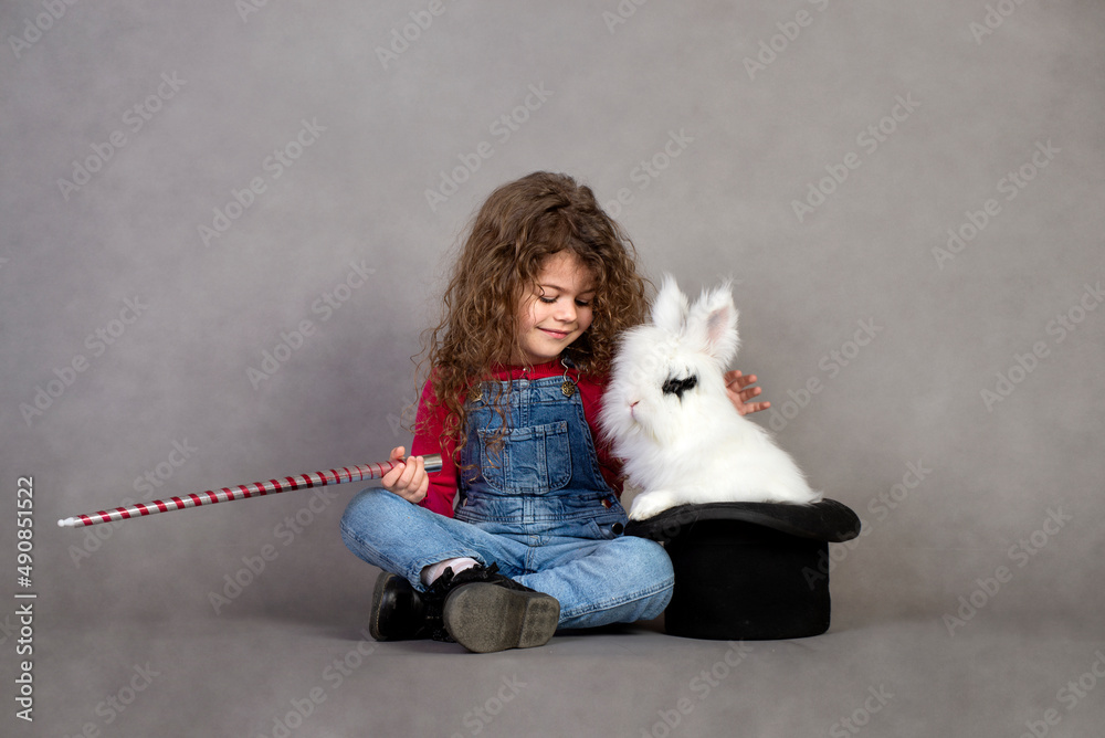Little girl playing with real rabbit, Bunny in a hat, they make magic Little girl playing with real rabbit, Bunny in a hat, they make magic