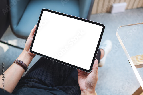 Top view mockup image of a woman holding digital tablet with blank white desktop screen in cafe