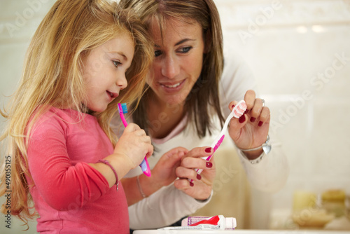 This will keep your teeth healthy. Cute little girl getting ready to brush her teeth with her mom.