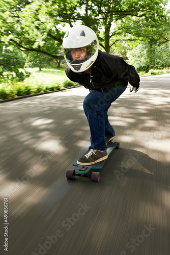 Building up speed. Shot of a man skateboarding down a lane at high speed on his board.