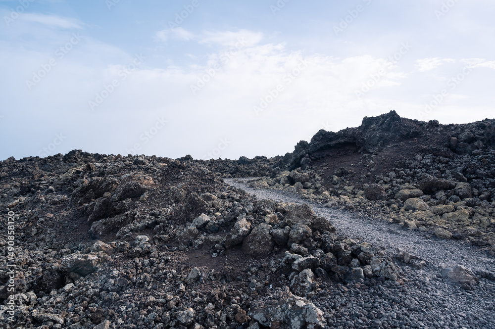 Footpath between lava with views of the Caldera Blanca volcano, Timanfaya, Canary Islands, Lanzarote, Spain