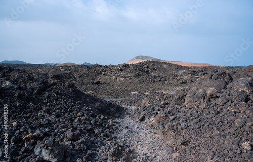 Footpath between lava with views of the Caldera Blanca volcano, Timanfaya, Canary Islands, Lanzarote, Spain