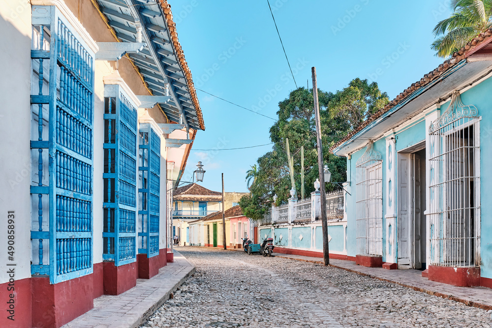 Fototapeta premium Cobblestone street with coloured buildings, wooden window bars in colonial old town Trinidad, Cuba