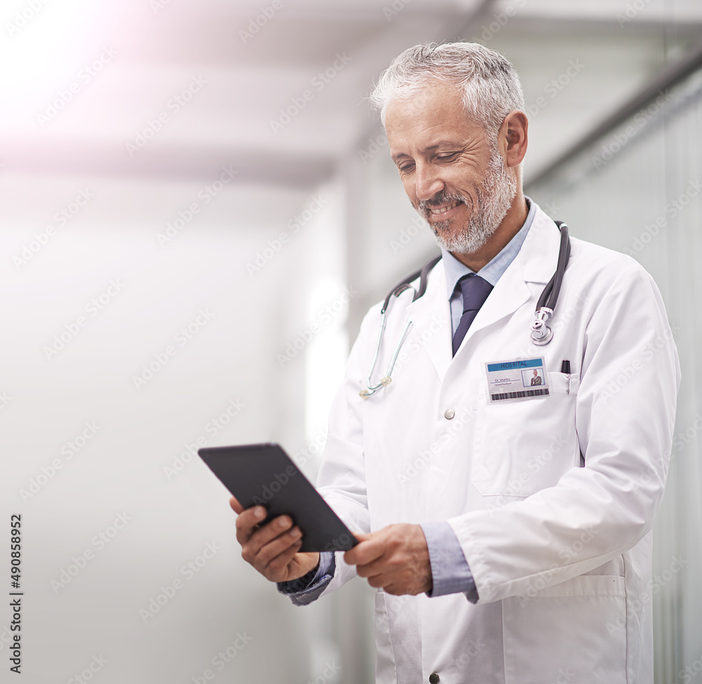 Medical records at the touch of a button. Shot of a mature doctor using a digital tablet in a hospital. Medical records at the touch of a button. Shot of a mature doctor using a digital tablet in a hospital.
