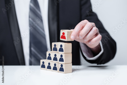 Businessman hand holding wood block with leader person icon. Leadership and success in business concept. photo
