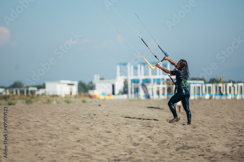 Woman using control bar to lift her kite up for kitesurfing