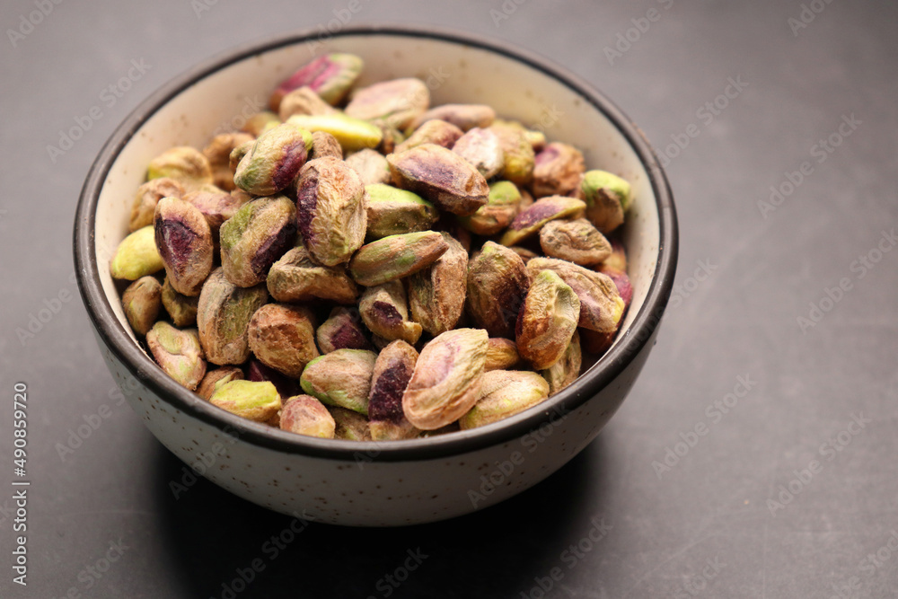 Peeled pistachio nuts in a bowl over black background. Baked pistachios pile, salt pistache, salted pista. Copyspace Peeled pistachio nuts in a bowl over black background. Baked pistachios pile, salt pistache, salted pista. Copyspace
