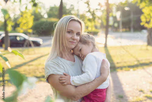 Mom and child outdoor. Happy mother and little daughter in the park on a sunny day at sunset.  Concept of tenderness, family single mother, flowers, smiles, hugs, mental health, harmony, peace