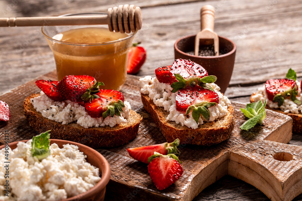 toasts or bruschetta with strawberry and mint on cream cheese ricotta. Delicious breakfast or snack, top view