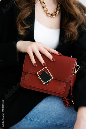 Small red handbag. Fashionable women's leather clutch bag with fabric strap.  Isolated on white background. Traditional clutch bag with brooch. bag made of red genuine fine leather. Front view. 