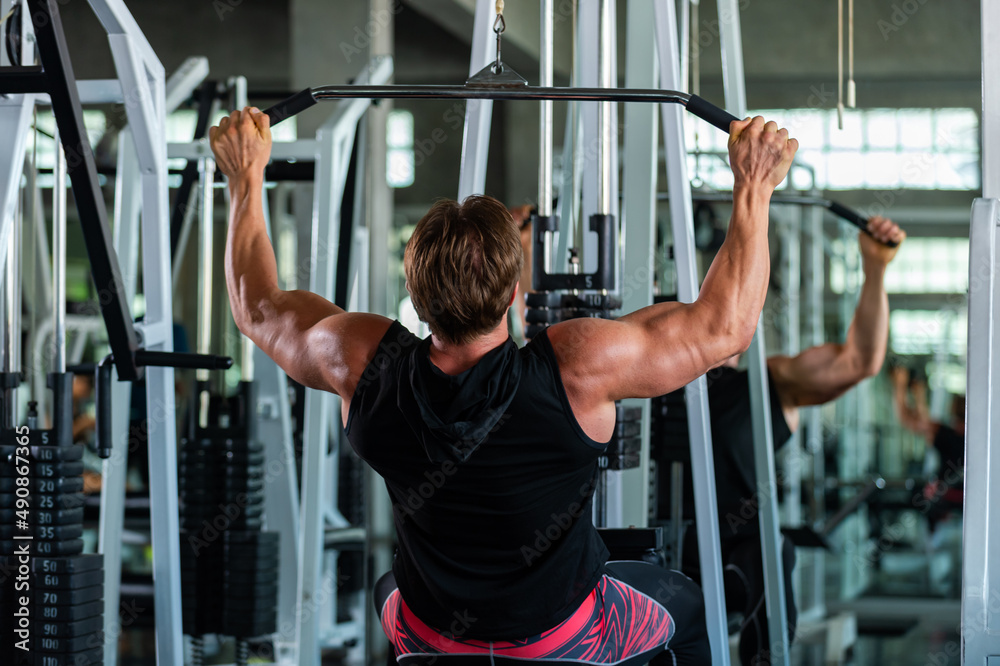 Strong Caucasian man athletic workout exercise pulling weight lifting machine at fitness club. Male bodybuilder do body building muscle weight training at sport gym. Health care motivation concept Strong Caucasian man athletic workout exercise pulling weight lifting machine at fitness club. Male bodybuilder do body building muscle weight training at sport gym. Health care motivation concept