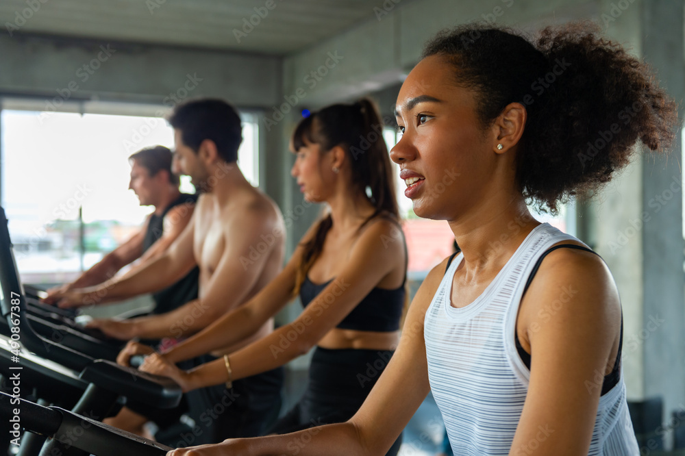 Group of Healthy athletic man and woman in sportswear workout exercise on cycling machine together at fitness gym. Male and female do sport training at sport club. Health care motivation concept