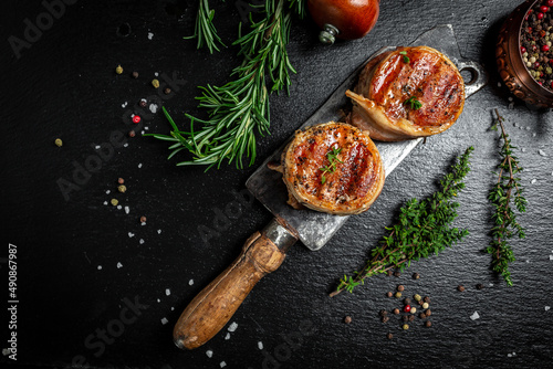 Premium Beef Steak. portion of juicy beef tenderloin steak covered bacon on dark concrete background with spices. Ketogenic diet food, top view photo