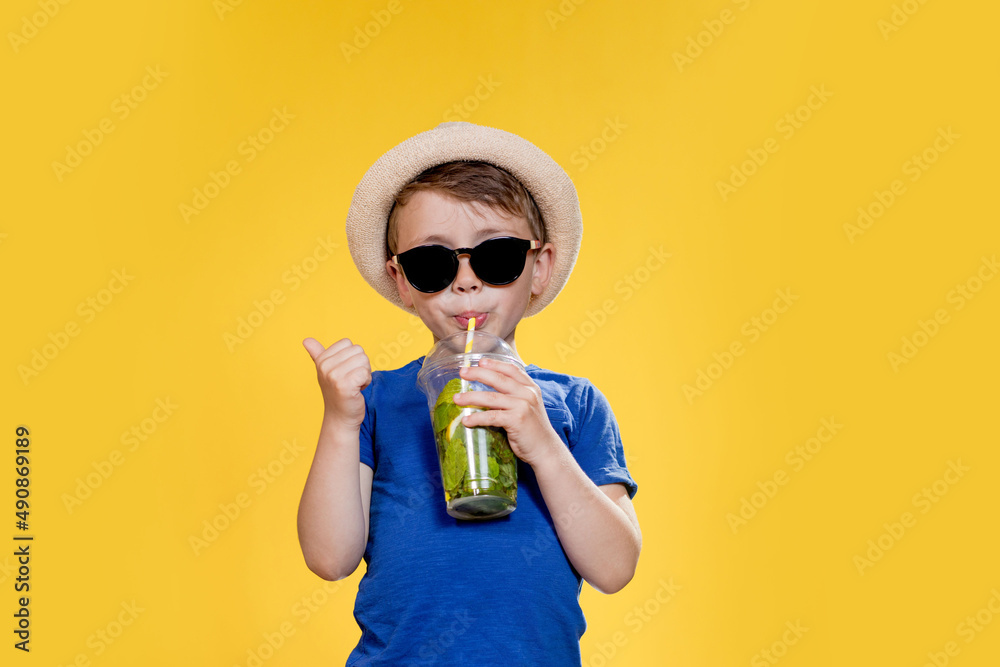 Cute boy Drink Mojito cocktail From Plastic Cup Over Yellow Studio Background Cute boy Drink Mojito cocktail From Plastic Cup Over Yellow Studio Background