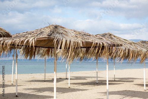 exotic beach on the beach with parasol. A lonely empty beach umbrella made of reeds. Beautiful dry branches of palm trees on the roof against the backdrop of the beach.
