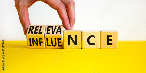 Influence or relevance symbol. Businessman turns wooden cubes and changes the word Influence to Relevance. Beautiful yellow table white background. Business influence or relevance concept. Copy space. photo